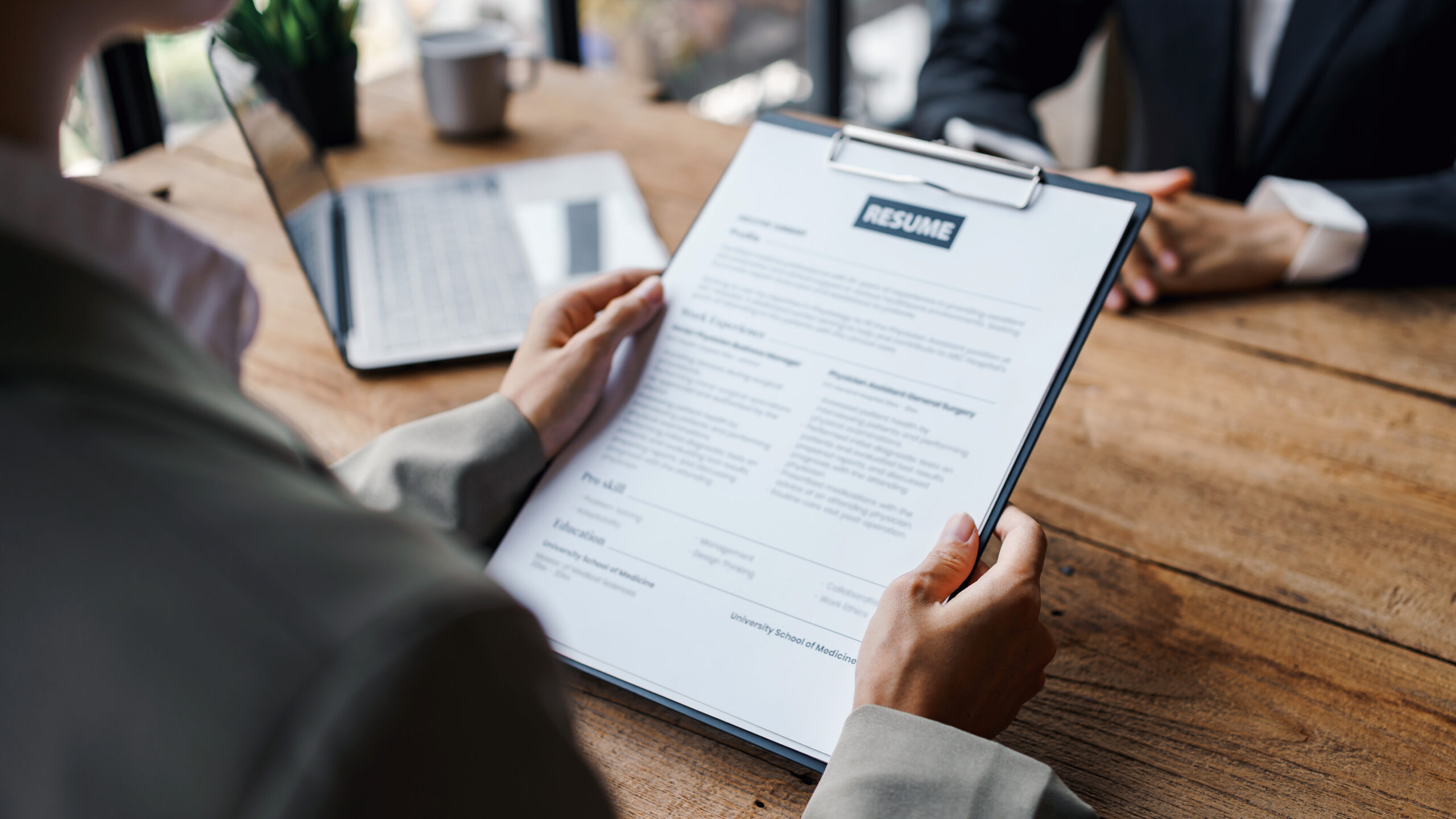 Close-up of a business owner reviewing a resume, representing the thorough and systematic recruitment process for software sales roles.