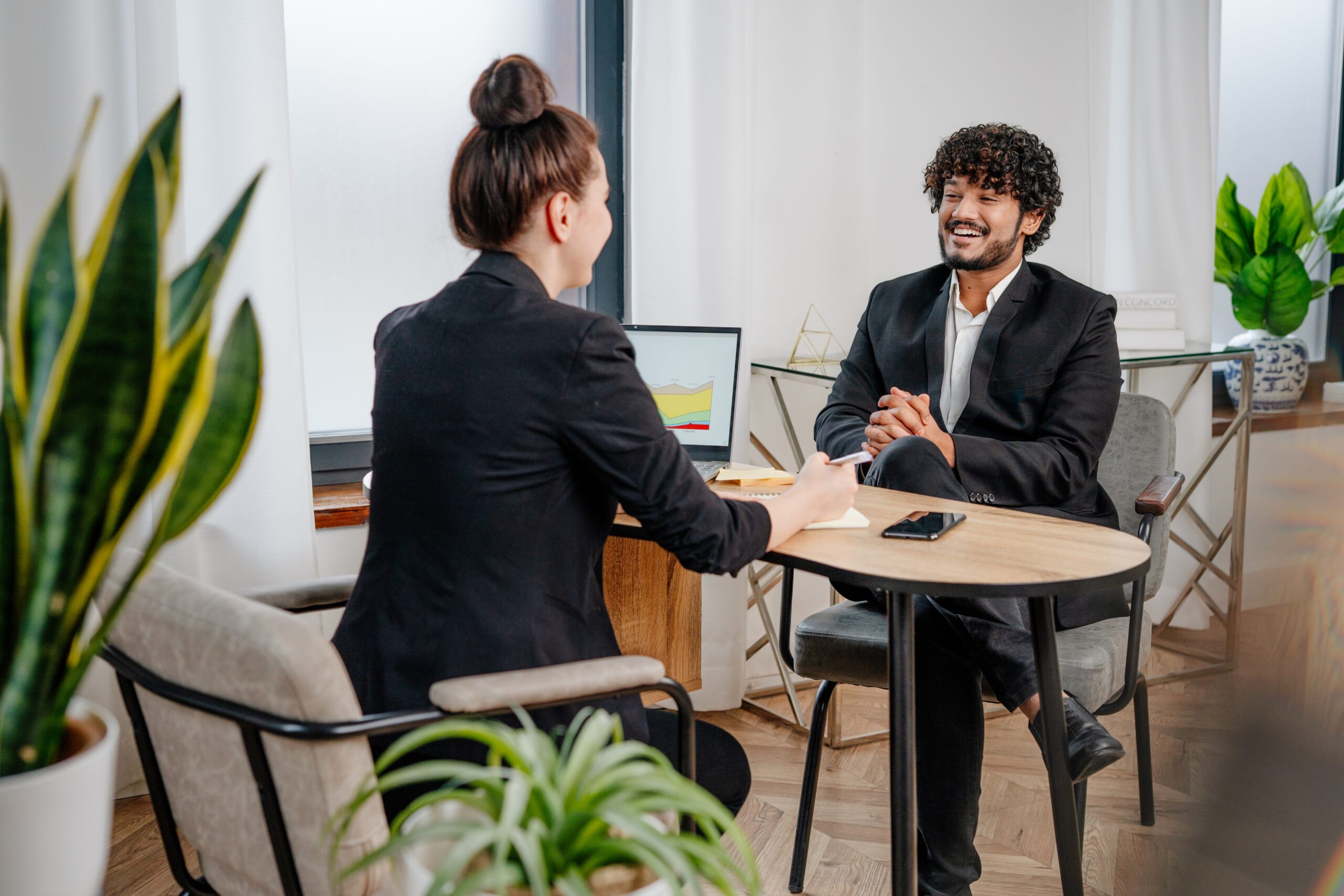 A professional sitting confidently in an interview setting. He is engaged in conversation with an interviewer, showcasing preparation and confidence. The image conveys the essence of acing a SaaS sales job interview.