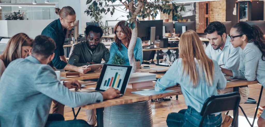 A diverse team of professionals collaborating in a modern workspace, discussing strategies for selling Edtech products and services.