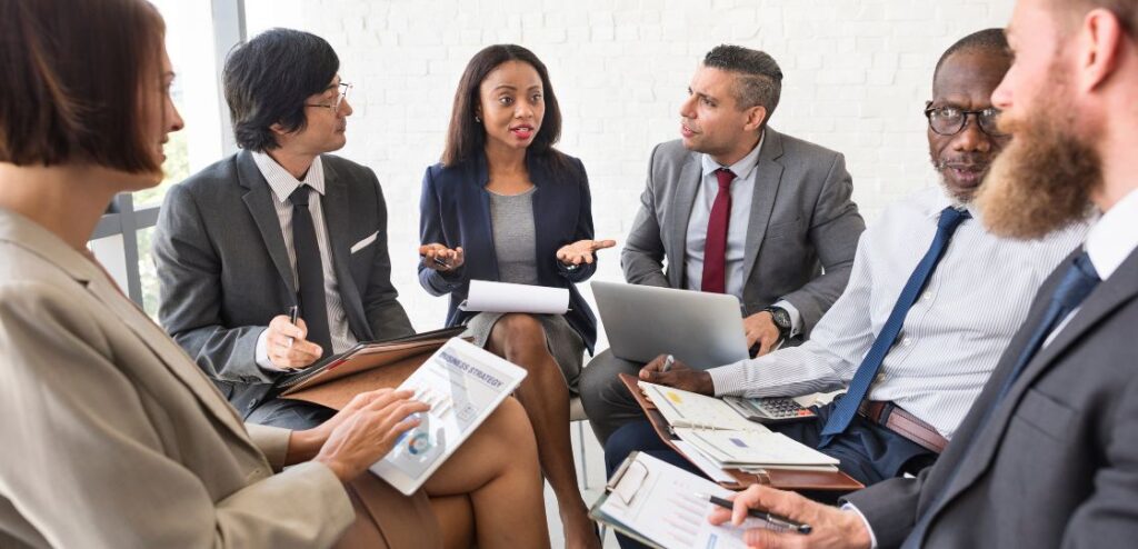 A diverse group of business professionals discussing cloud sales strategies in a modern office setting.