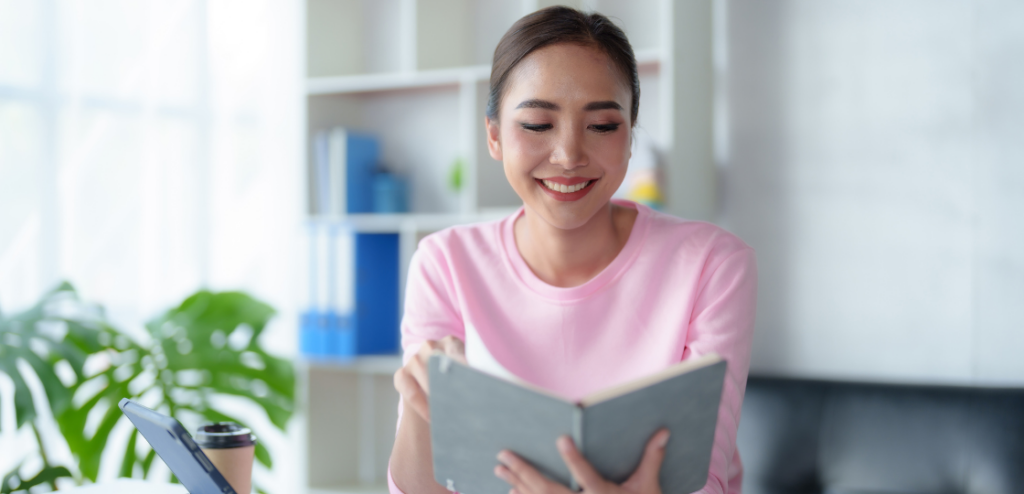 A person sitting at a desk, diligently reading a SaaS sales guidebook, symbolizing the process of learning about SaaS sales strategies and techniques without prior experience